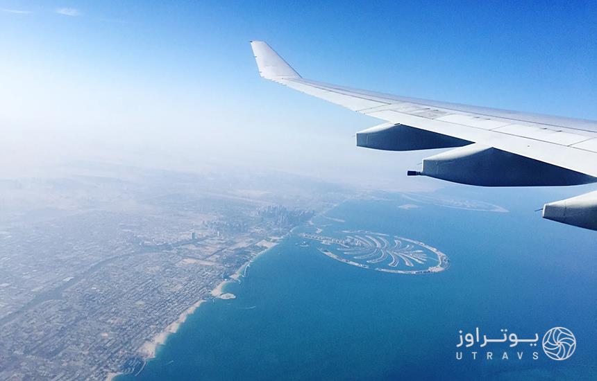 بخشی از بال سفید هواپیما در آسمان که زیر آن، جزایر مصنوعی دبی دیده می‌شود.
